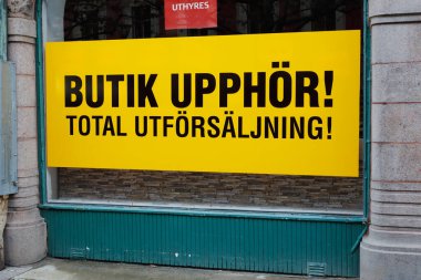 Sign in store window with a message in Swedish that it is a vacant store for rent and that there is a sale going on due to the store ceasing. clipart