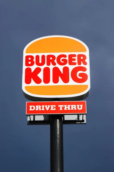 Eskilstuna, Sweden - May 17, 2021: Low angle view of the new rebranded Burger King logo on a pole outside the restaurant with drive thru isolated against a dark sky.