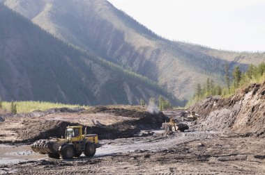Buldozerler ve tekerlek yükleyiciler iş başında. Madencilik. Buldozerler dağlık ormanlardaki toprağı kesiyor ve tekerlek yükleyicileri toprağı taşıyor.