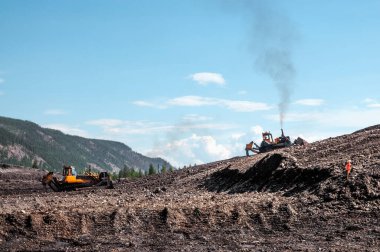 Buldozerler dağlık bir ormandaki toprağı kestiler. Madencilik