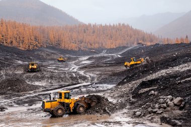 Buldozerler ve tekerlek yükleyiciler iş başında. Madencilik. Buldozerler dağlık ormanlardaki toprağı kesiyor ve tekerlek yükleyicileri toprağı taşıyor.