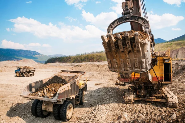 Dump truck and excavator at work. Mining.Excavator loads mountain soil into the body of a dump truck