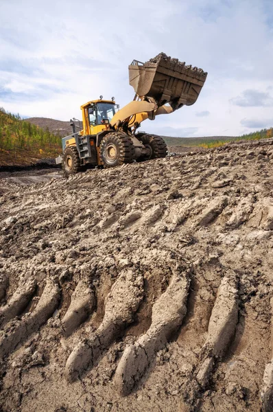 Wheel loader at work. It transports gold-bearing mountain soil to hopper of  washing device. The gold mining industry in Eastern Siberia widely uses such equipment as front loader, bulldozer, excavators of all types mining dump trucks, wheel loaders