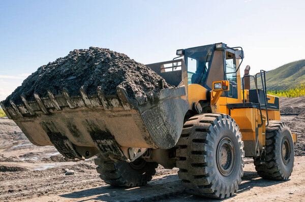 Wheel loader at work. It transports gold-bearing mountain soil to hopper of  washing device. The gold mining industry in Eastern Siberia widely uses such equipment as front loader, bulldozer, excavators of all types mining dump trucks, wheel loaders 