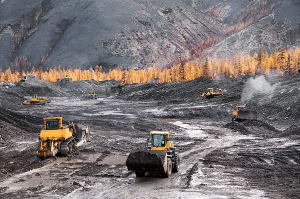 Bulldozers and wheel loaders at work. Mining.Bulldozers cut the topsoil in mountainous forested areas and wheel loaders transport the soil