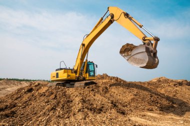 Kazıcı bir kova toprak topladı ve bir çöp kamyonunun gelmesini bekliyor.