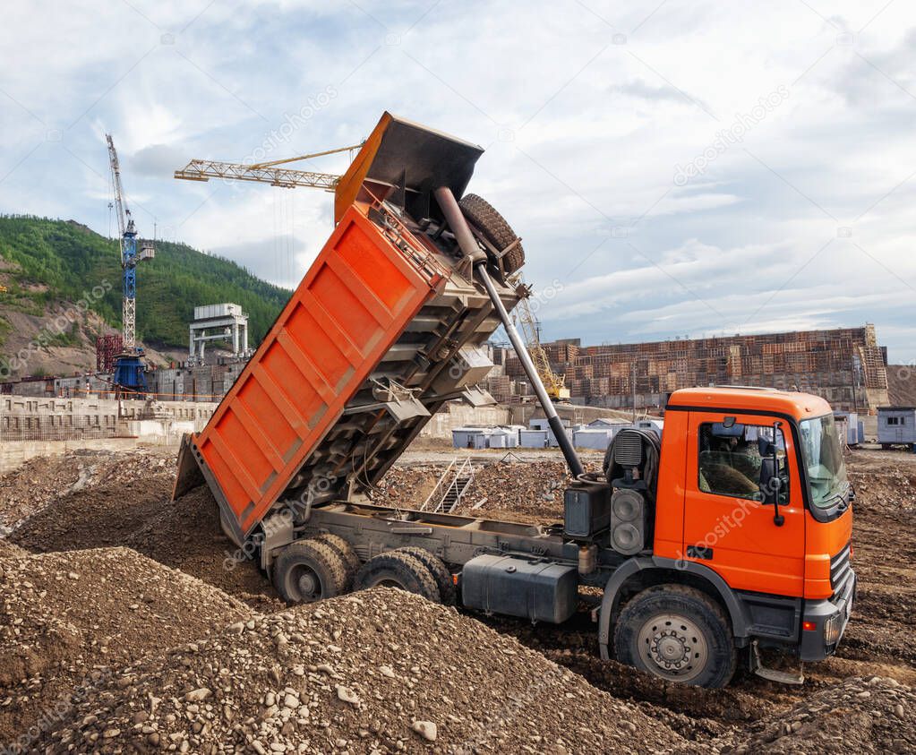  Dump truck unloads mountain soil in an industrial area, in the area of a construction site