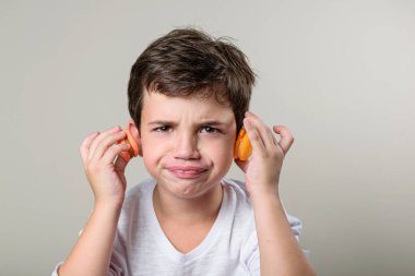6 year old child putting a macaron in each ear and making a funny face. clipart