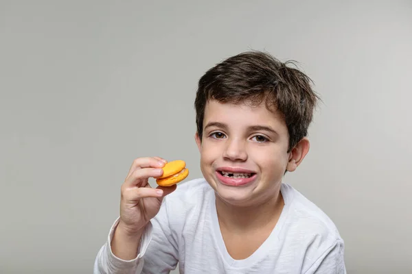 Letý Chlapec Drží Žlutý Makrón Usmívá — Stock fotografie
