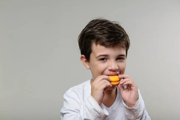 6 yaşındaki çocuk sarı bir badem kurabiyesini ısırıyor..