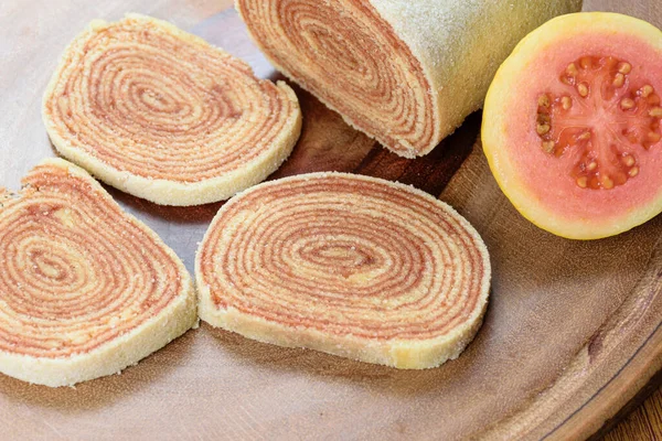 Tahta bir tahtanın üzerindeki guavaların yanına dilimlenmiş kek (bolo de rolo) yakın plan.