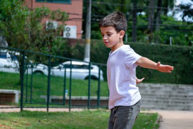 6 yaşında kolları açık ve ağaç gövdesinde dengede duran bir çocuk..