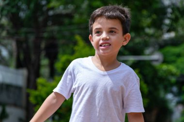 Ön dişi olmadan gülümseyen ve geleceğe bakan 6 yaşındaki bir çocuğun yakın çekimi..