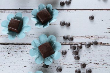 Çikolatalı şekerler beyaz bir masada, çikolata parçacıklarının yanında.).