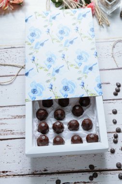 Beyaz bir masada, sicim ipi ve çikolata parçacıklarının yanında çikolata dolu bir kutu..