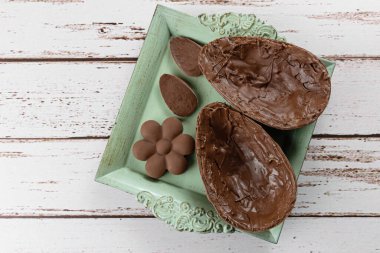 İki parça çikolatalı Paskalya yumurtası, küçük eski bir tepside. Mini çikolataların yanına (üst görünüm).