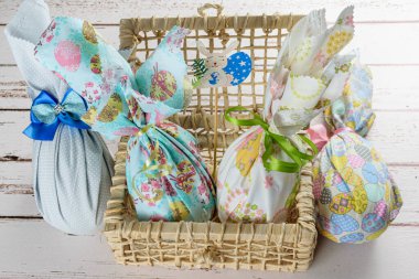 Renkli kumaşlar ve kurdele kurdeleleriyle doldurulmuş çikolatalı Paskalya yumurtaları. Bir sepet mısır kamışının üzerinde.