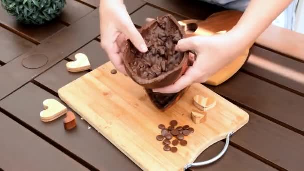 Donna che rompe e mostra metà di un uovo di Pasqua al cioccolato fondente con mandorla croccante. — Video Stock