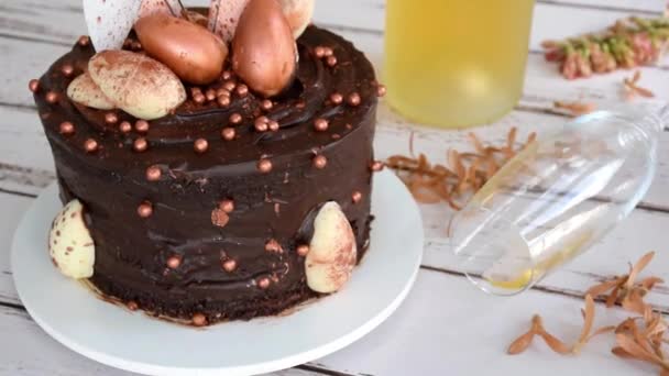 Ein Glas Sekt rollt neben einem Osterschokokuchen, zoomen Sie rein. — Stockvideo