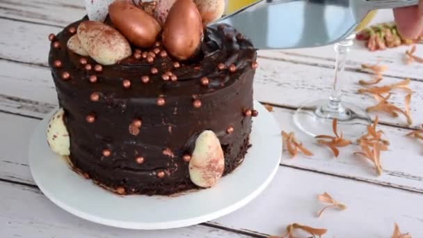 Spatola d'argento taglio una fetta di torta al cioccolato di Pasqua con glassa e riempimento con ganache scure, zoom in. — Video Stock