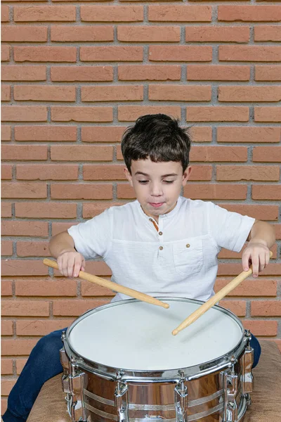 Sedmileté Dítě Hraje Bubny Dělá Legrační Obličej Cihlová Zeď Pozadí — Stock fotografie