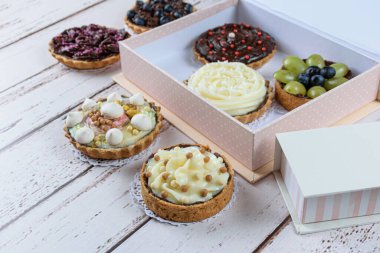 Yağlı hamurlu mini turta, çikolatalı ganache dolgu ve hindistan cevizi kreması. Diğer turta ve kutularla çevrili..