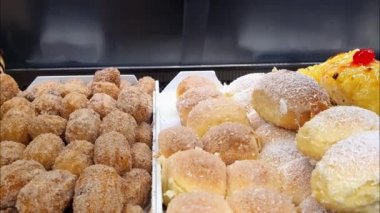 Çeşitli tatlı ekmekler, üzerine şeker ve granüllü hindistancevizi, sarısı krema, vişne ve limon..