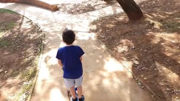 8 year old boy walking with his scooter in a public square on a sunny day (top view). — Stock Video