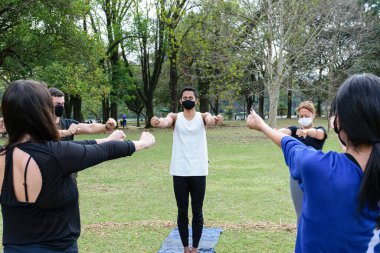 Sao Paulo, Sao Paulo, Brezilya - Temmuz 04, 2021: 28 Brezilyalı genç adam halka açık bir parkta güneşli bir günde yoga dersi veriyor..