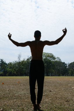 Halka açık bir parkta sırtı ve kolları açık genç Brezilyalı bir adamın silueti..