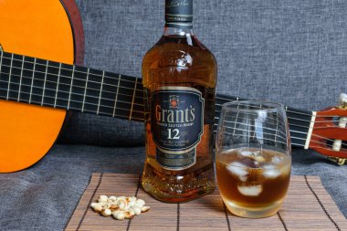 Sao Paulo / Sao Paulo / Brasil - 01 Ağustos 2020 'de: Arka planda gitar ve fıstık parçasının yanında viski şişesi.