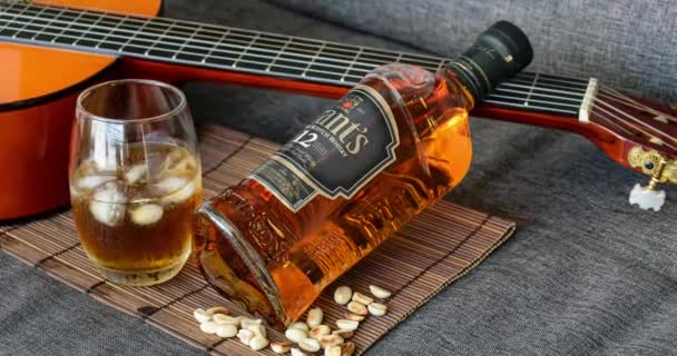 Sao Paulo / Sao Paulo / Brasil - el 01 de agosto de 2020: Primer plano de una botella de whisky apoyada en el cuello de la guitarra _ zoom. — Vídeos de Stock