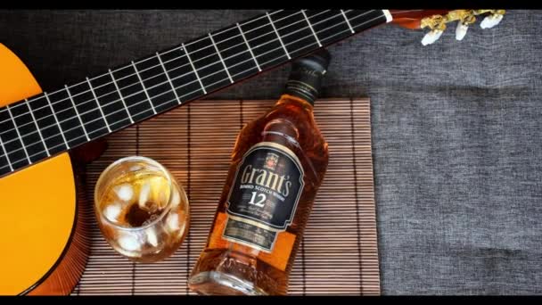 Sao Paulo / Sao Paulo / Brasil - w dniu 01 sierpnia 2020 r.: butelka whisky i szklanka obok Guitar _ zoom in (widok z góry). — Wideo stockowe