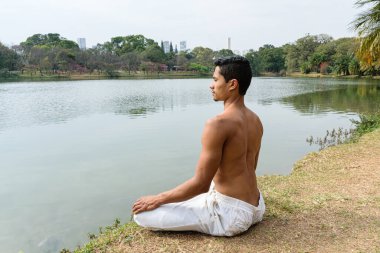 Sao Paulo, SP, Brezilya, 16 Temmuz 2021. 40 yaşında sırtı yırtık bir kadın halk parkında yoga pozisyonunda oturuyor..