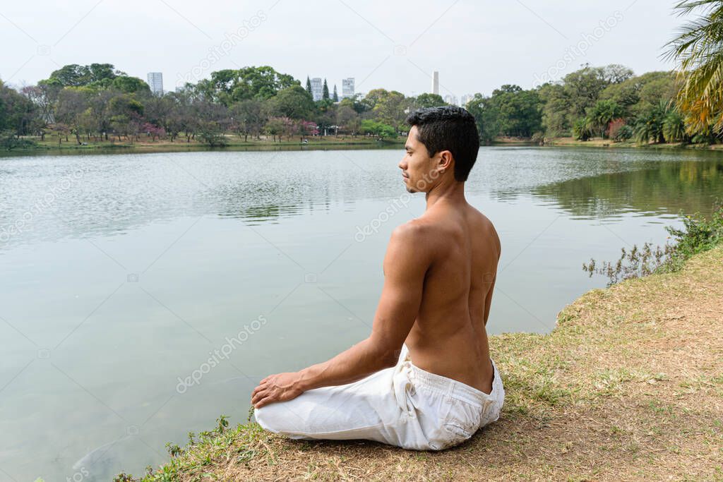 Sao Paulo, SP, Brazil, July 16 2021. 40 year old woman with ripped back sitting on her feet in a yoga position in a public park.