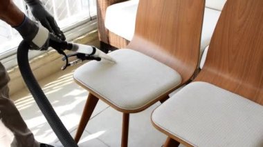 Profesyonel. Sandalyenin beyaz koltuğunu temizlemek için özel bir süpürge kullanıyor..