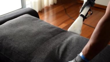 Profesyonel. Kanepe yastığını temizlemek için özel vakum kullanıyor..