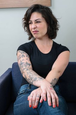 Brezilyalı bir kadın, dövmeli, elleri çapraz ve yan tarafa bakıyor, küçümsediğini gösteriyor..