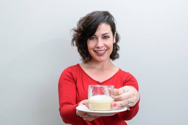 Gülümseyen Brezilyalı kadın kucağında bir fincan kapuçino ikram ediyor..