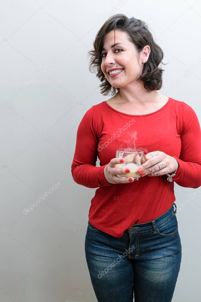 Brazilian woman turning her head and smiling and holding a mug of cappuccino.