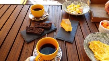 Sağlıklı bir kahvaltı masası servis eden kadın, jambonlu omlet, kurabiye ve muzlu kek, papaya, kahve, kahve ve çilekli reçel..