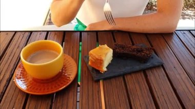 Bir parça muzlu keki çatallayan kadın. Kurabiye kekinin ve bir fincan sütlü kahvenin yanında ağır çekimde servis edilir..