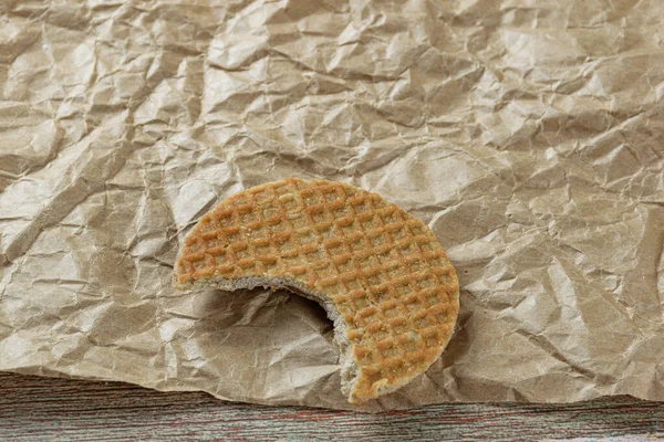 Stroopwafel yakın plan kahverengi kağıtta bir ısırık ile.