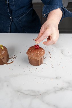 Bir pasta şefi taze kirazı küçük panettone 'un üzerine yerleştiriyor _ dikey.