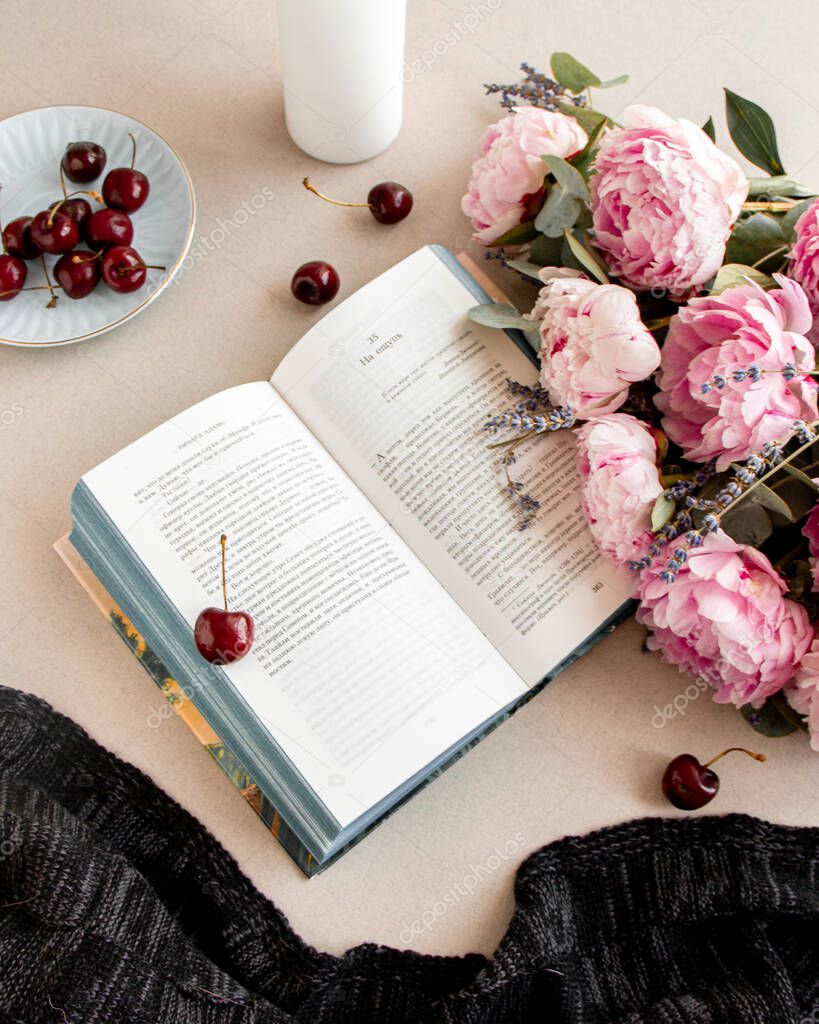Book and cherry with peonies on a table