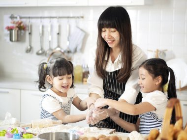 Asyalı kızlar annelerine mutfakta pastane için yardım ediyorlar..