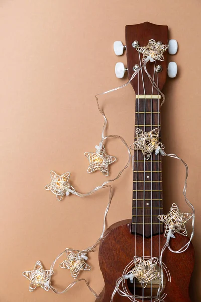 祭りの組成ウクレレギターとテキストのためのベージュの背景空間にクリスマスガーランドの光 — ストック写真