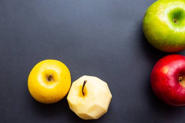 Elmalar yeşil, sarı, kırmızı ve elma kabuksuz siyah arka plan. Fotokopi alanı olan sağlıklı gıda kavramı