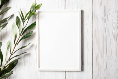 Beyaz tahta bir masanın üzerinde okaliptüs filizi olan beyaz fotoğraf çerçevesi. Minimalist, nazik bir model.