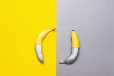 Sarı-gri arka planda gümüş renkli muzlar. Minimalist soyut gıda görüntüsü